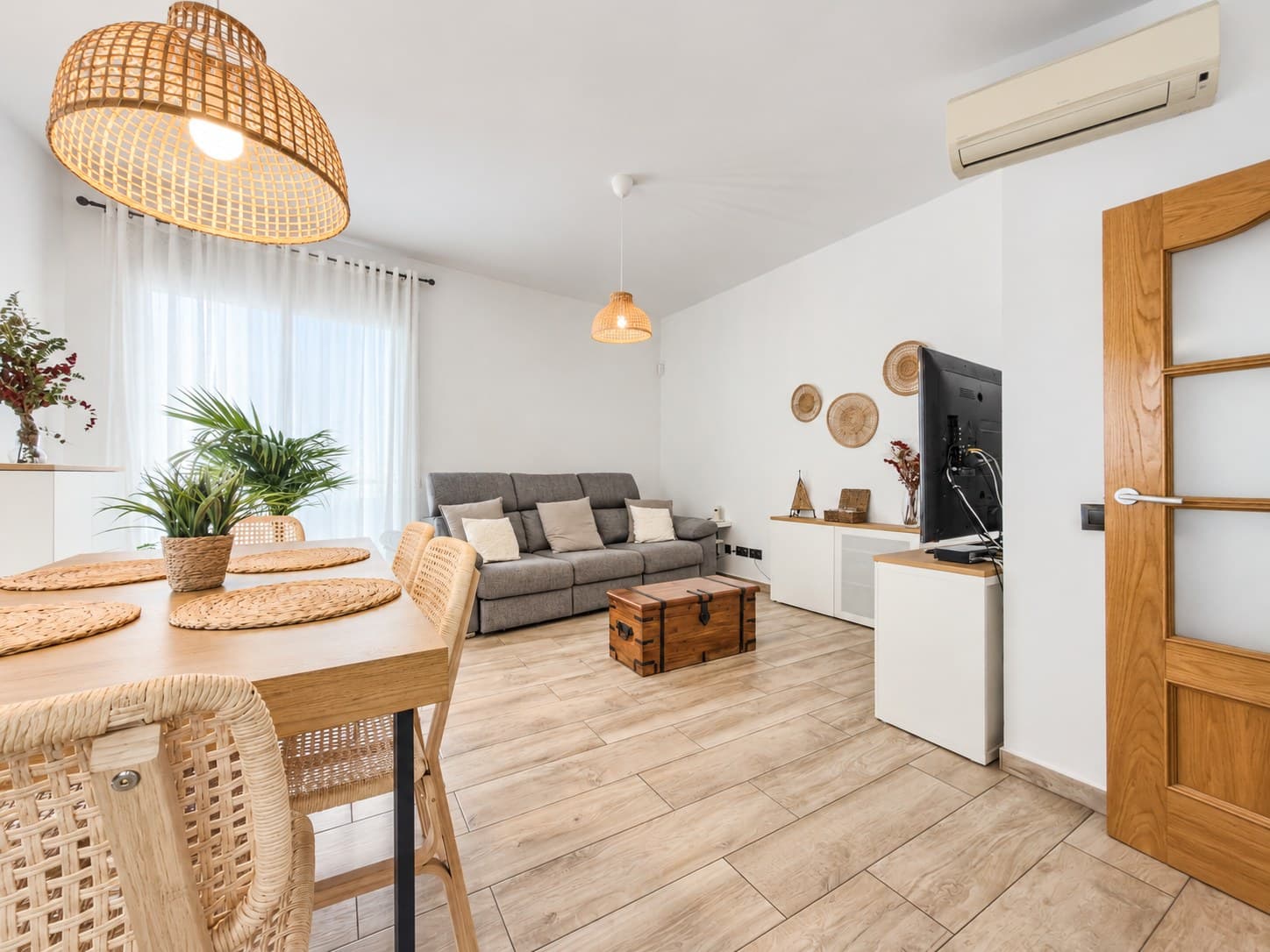 Sala d'estar lluminosa amb un sofà gris i la taula del menjador