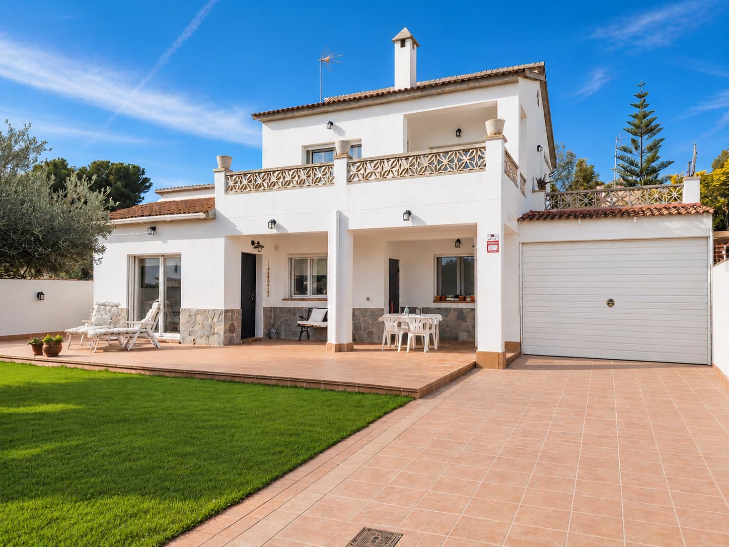 Façana blanca d'una casa amb porxo i jardí